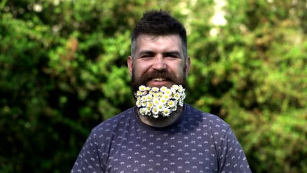 Bel homme avec barbe de fleurs sur le parc de fleurs de printemps. Fermez le visage masculin du printemps. Homme barbu et élégant. Barbe fleurie. — Video