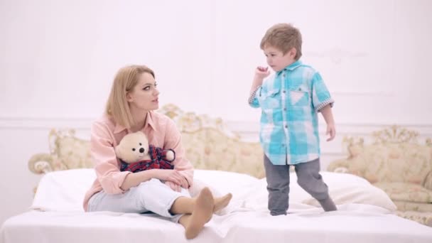 Happy carefree family having fun at home. Smiling mother and little child enjoying weekend together playing on comfy bed in cozy bedroom. Mom and child son talking in bedroom. — Stock Video