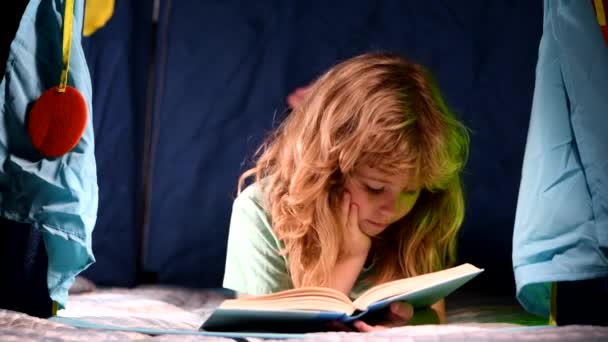 Dzieci czytają bajki. W kierunku wiedzy. Chłopak z książką czyta historię na tle ciemnego pokoju. Dziecko lubi uczyć się i czytać książki. Koncepcja księgarni. Literatura dla dzieci. — Wideo stockowe