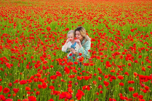 Bella madre e figlia nel campo di fiori di papavero primavera. Famiglia felice che riposa su un bellissimo campo di papaveri. Mamma tiene sua figlia nel prato fiorito. Design primaverile. — Foto Stock