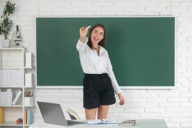 Sınıfta tebeşirle yazı yazan gülümseyen genç üniversite öğrencisinin portresi..