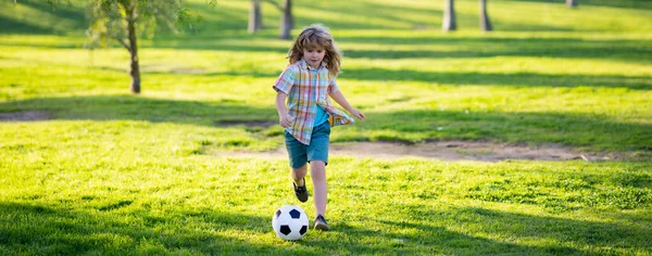 Молодой футболист в парке. Мальчик пинает футбольный мяч, плакат. — стоковое фото
