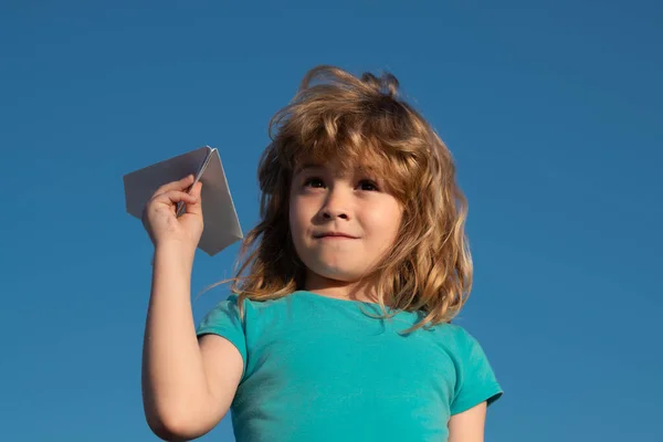 Divertido menino sonha com aviador enquanto joga um avião de papel no céu. Sonhador infantil, avião de papel, avião de brinquedo. Imaginação, liberdade das crianças. — Fotografia de Stock