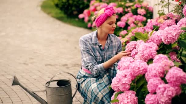 Jardinage ib arrière-cour. Heureux jeune jardinier qui sélectionne des plantes hortensias. Femme blonde gaie plantant des fleurs dans le jardin. — Video