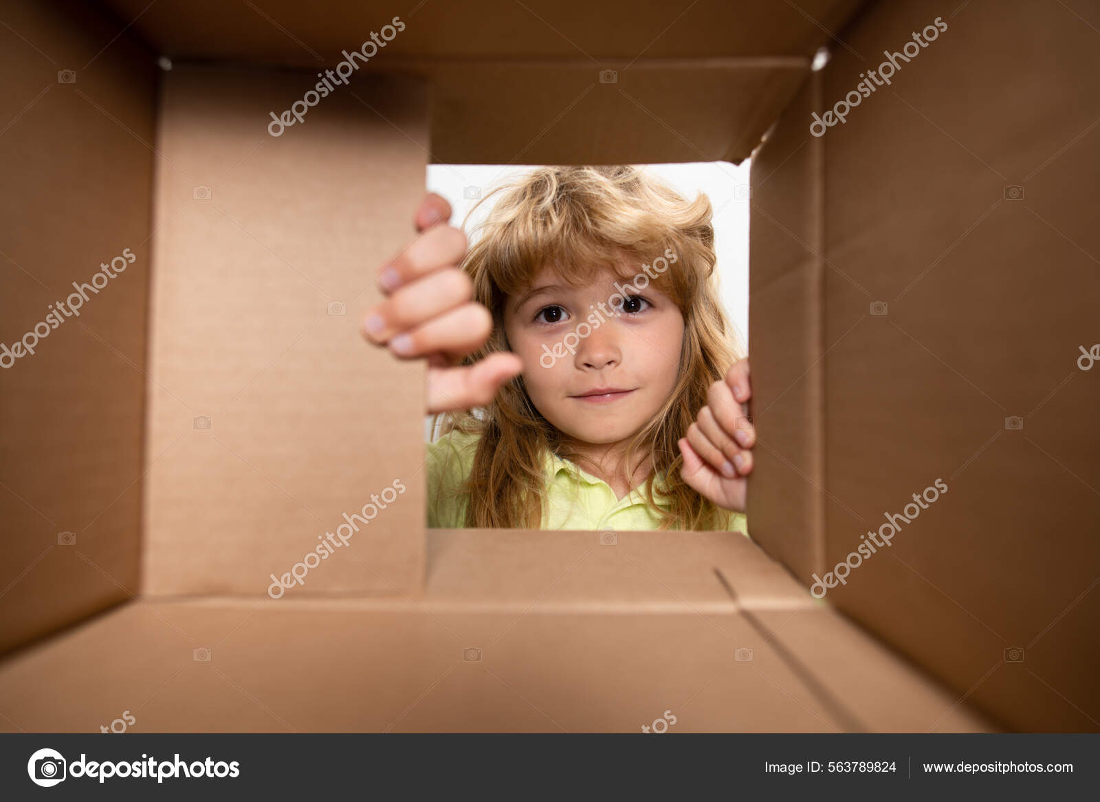 Surprised child boy unpacking, opening carton box and looking inside ...
