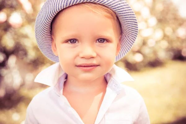 Nettes Kind auf dem grünen Rasen im Sommerpark. Babygesicht Nahaufnahme. Lustige kleine Junge Nahaufnahme Porträt. Blondes Kind, lächelndes emotionales Gesicht. — Stockfoto
