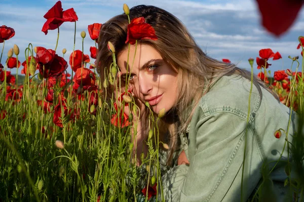 Portrait of a beautiful woman in a poppies meadow. Beauty girl resting in the field with poppy flowers. The woman have fun and enjoy the freedom. — Stock Photo, Image