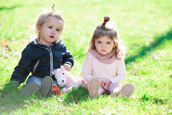 Baby leker i grönt gräs. Barn har kul på familjepicknick i sommarträdgården. Broder och syster leker tillsammans på en grön äng. Glada barn som leker sittande på grönt gräs i vårparken. — Stockfoto