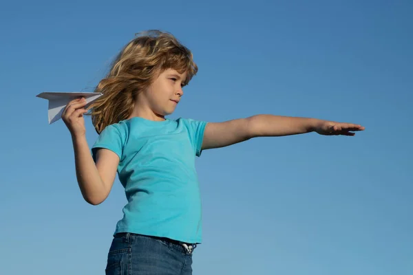 Niño con avión de papel contra cielo azul. Niño soñando, lanzando avión de papel, avión de juguete. Imaginación, libertad de los niños. —  Fotos de Stock