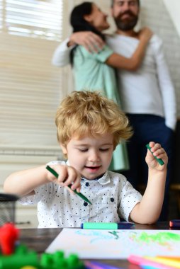 Anne ve baba çocuklu resim çiziyor. Aile eğlencesi, mutlu anne, baba ve küçük çocuk. Evde mutlu ve sevgi dolu bir aile. Çocukluk eğitimi, çocukların sanatsal becerileri..