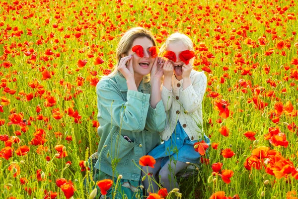 Счастливой весны. Мать и дочь обнимаются на маковом лугу. Мама и девочка отдыхают в поле с маковыми цветами. Женщина и девочка веселятся и наслаждаются свободой. — стоковое фото