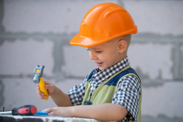 Kid in hard hat holding hammer. Little child helping with toy tools on construciton site. Kids with construction tools. Construction worker. Repair home. — Stock Photo, Image