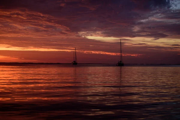 Calm sea. Sunset with large yellow sun under the sea surface. Calm ocean with sunset sky and sun through the clouds over. Calm ocean and sky background. — Stock Photo, Image