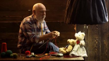 Yaşlı büyükbaba evde örgü iğneleriyle örüyordu. Son sınıf hobisi. Emeklilik toplantısı konsepti.