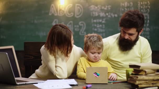 Mãe e pai com criança escrevendo em casa escola. Menino bonito aprendendo com os pais. Mãe pai e filhos desenho em casa escola classe. — Vídeo de Stock