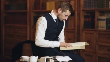 Kütüphanede arka planda kitapları olan bir adam. Orta yaşlı bir adam kütüphanede kitap okuyor. Klasik takım elbiseli iş adamı kitap okudu. Moda işçileri. Hukuk ve adalet kavramı.