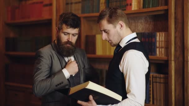 Företagsanställda chattar i biblioteket. Professor och student diskuterar i biblioteket. Vetenskapsmän pratar. Man intelligens talar nära bokhyllan. — Stockvideo