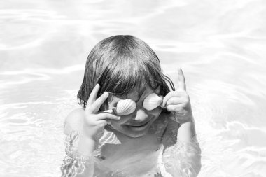 Denizde oynayan mutlu çocuk. Çocuk dışarıda eğleniyor. Yaz tatili ve sağlıklı yaşam tarzı konsepti. Kabuklu gözler..