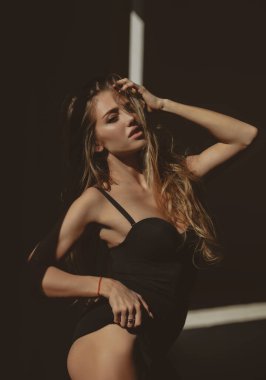 Siyah arka planda poz veren zarif genç bir kadın. Işık ve gölge. Güzel bir kadının portresi. Moda mankeni, zarif kızın siyah modası. Yüksek moda görünüş.