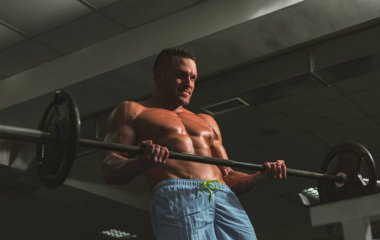 Kaslı adam yaya geçidinde. Halter kaldıran formda bir adam. Crossfit spor salonunda çalışan genç bir adam. Sporcu adam egzersiz yapıyor..