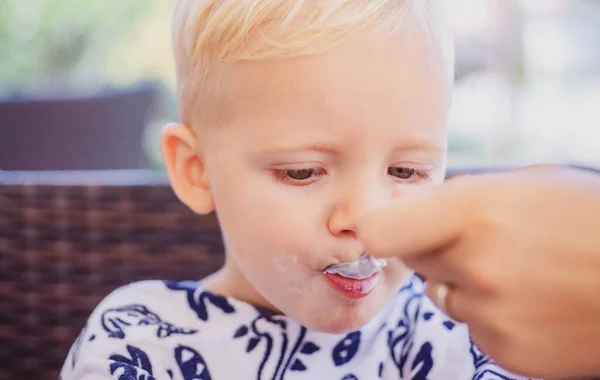 Kindervoeding. Kleine jongen voeren met een lepel. Vaderschap, moeder of zus met kind. — Stockfoto