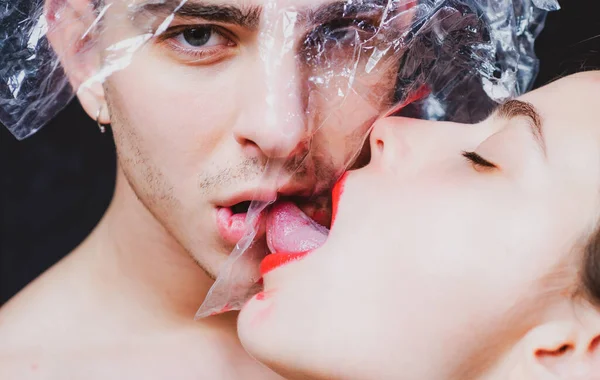 Oraal condoom concept. Bescherming van de gezondheid. Gezondheidsbescherming. Seksueel overdraagbare ziekten. Seksuele activiteit. Seks gezondheid. Een paar kusjes door doorzichtig plastic. Meisje sexy tong likken jongen. Veilige seks — Stockfoto