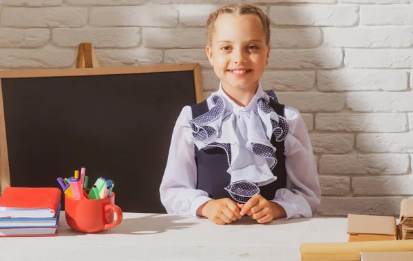 Mosolygó iskolás lány iskolai egyenruhát visel az iskolában. Aranyos iskolás lány portréja az iskolában. Oktatás és tanulás a gyermekek számára. — Stock Fotó