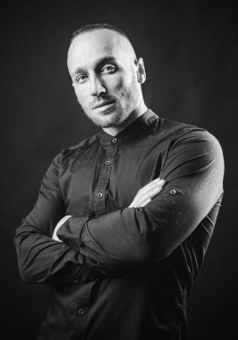 Çapraz kollu ciddi bir adam içeride poz veriyor. Moda erkek modeli..