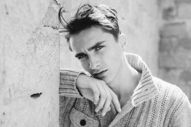 Gri duvara karşı tatmin olmuş genç bir adamın portresi. Gri arkaplandaki modaya uygun Latin adamın yüzünü kapat.