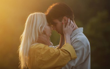 Şehvetli aşıklar gün batımında sarılıp öpüşüyorlar. Genç şehvetli kız arkadaşı, erkek arkadaşından tutkulu bir öpücük aldığı için mutlu. Yakışıklı genç adam kadınını kucaklıyor ve öpüyor..