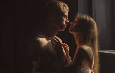 Birbirine aşık romantik bir çift birbirine bakıyor, siyah arka planda sarılıp öpüşüyorlar..