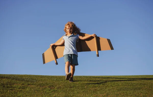 Joli garçon rêveur jouant avec un avion en carton sur le ciel. Enfance. Fantaisie, imagination. — Photo