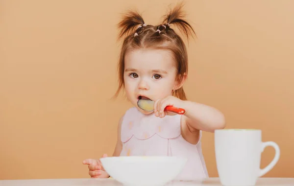 Linda comida para bebés, bebés comiendo. Feliz bebé niña con cuchara se come a sí misma. — Foto de Stock