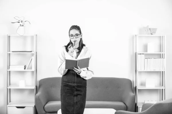 Denkendes Studentenporträt einer jungen Buchhalterin in formeller Kleidung, die am Büroarbeitsplatz Notizbuch oder Notizblock in der Hand hält. Erfolgreiche Managerin, schöne Sekretärin. — Stockfoto