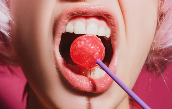 Ağzında kırmızı lolipop şekeri tutan pembe rujlu yakın plan kadın dudakları. Yüzünde lolipop var.. — Stok fotoğraf