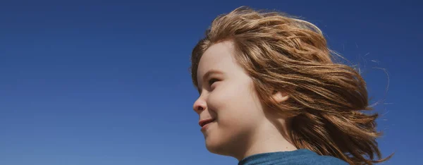 Retrato de um pequeno menino loiro olhando para o céu azul com espaço de cópia, banner close-up. Cara de miúdos giros. Criança emocional positiva. — Fotografia de Stock