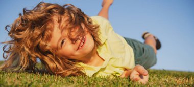 Yeşil çimlerde oynayan mutlu çocuk. Baharın bahçesinde komik bir çocuk. Çocuk günü konsepti.