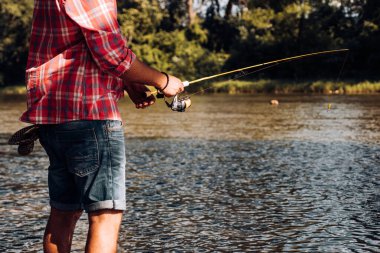 Balıkçı, dağ nehrinde olta balıkçılığı yapıyor. Ormandaki nehirde alabalık avlayan bir balıkçı..