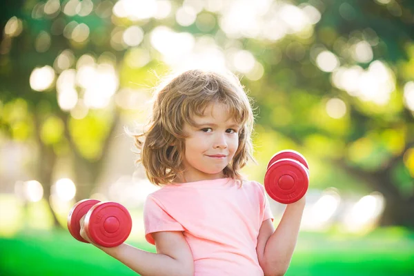 Fitnesskind. Porträt eines sportlichen kleinen Jungen mit Hanteln im Park. Fitnesstraining. Kindersportler, Aktivität in der Kindheit. Kindersport und Fitness. — Stockfoto