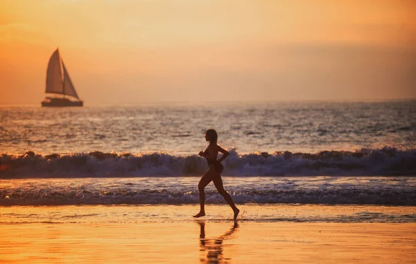 サンセット時にビーチで走るランナー女. — ストック写真
