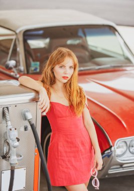 Retro Car. Benzin istasyonundaki kız. Kadın arabaya yakıt ikmali yapıyor. Kırmızı retro otomobil.