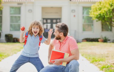 Öğretmenler günü. Baba oğul okul parkında yürüyorlar. Çocuğunu okula götüren ebeveyn.