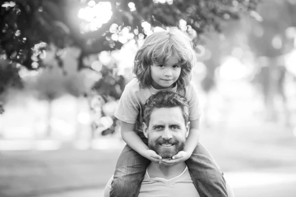 Vader geeft zoon een lift terug in het park. Portret van een gelukkige vader die zijn zoon meelift op de schouders. Schattig kind met papa outdoor. — Stockfoto