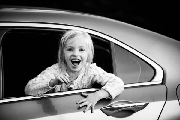 Emocionada niña admirando las miradas del coche en la calle. Linda niña sonriendo y divirtiéndose para viajar en coche . — Foto de Stock