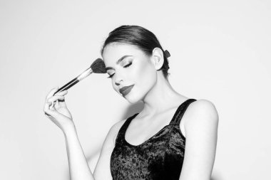 Temiz ve taze ciltli güzel bir kadın. Kozmetik fırçayla allık sürüyor..