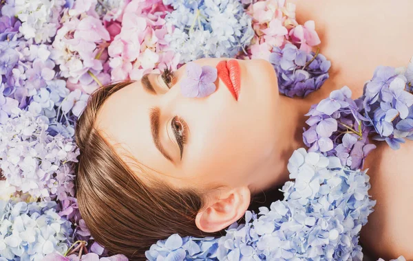 Natuurschoon. Een vrouw die op bloemen ligt. Blossom. Make-up cosmetica en huidverzorging. Meisje met hortensia bloemen. — Stockfoto