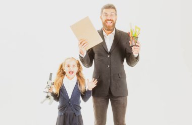 Stüdyoda heyecanlı öğretmeni olan ilkokul öğrencisi, izole edilmiş. Kitabı olan öğretmen ve okul malzemesi olan kız öğrenci beyaz arka planda izole edilmiş..