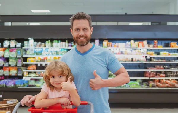 Padre e figlio comprano verdure fresche al supermercato con i pollici in su. Famiglia in negozio. — Foto Stock