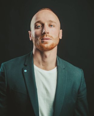 Kendine güvenen bir iş adamı. Genç adamın kameraya baktığı bir stüdyo fotoğrafı. Siyahta yakışıklı adam. Biçim ve eğilim.