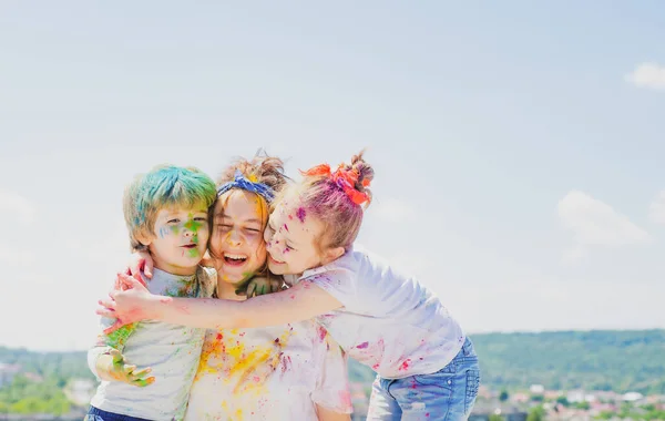 Boldog gyerekkort. Gyerekportré színes púderholiban. A gyerekek arca színesre festve. Gyerekek színes fröcskölés party. — Stock Fotó